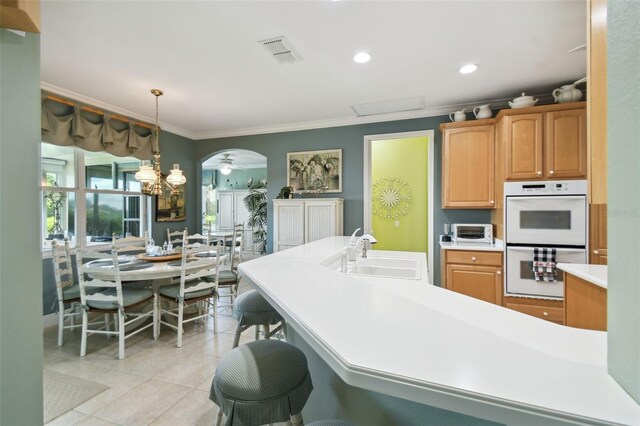 201 Largo Dr, Kissimmee, FL 34759 - kitchen featuring white double oven, ornamental molding, light countertops, light tile patterned floors, and arched walkways