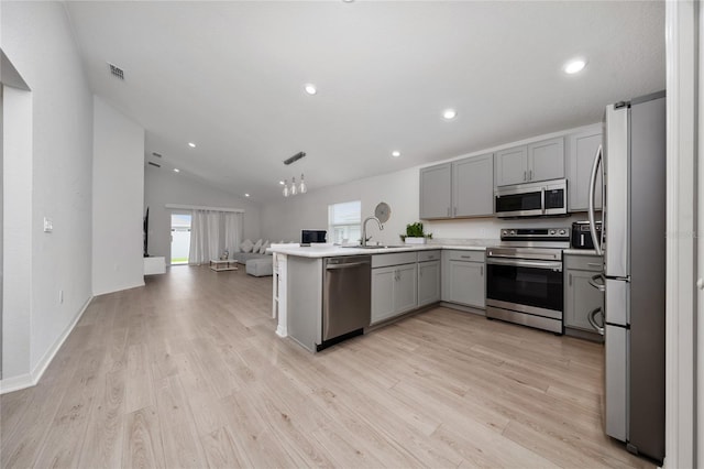1719 Daystar Dr, Haines City, FL 33844 - kitchen featuring stainless steel appliances, gray cabinets, open floor plan, a peninsula, and light wood-type flooring