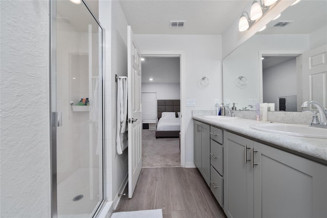 1719 Daystar Dr, Haines City, FL 33844 - full bathroom featuring ensuite bath, wood finished floors, double vanity, a shower stall, and a textured wall