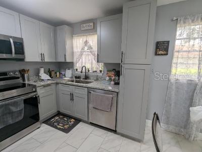 946 Delano Ct, Kissimmee, FL 34758 - kitchen featuring stainless steel appliances, a sink, light marble finish flooring, light stone countertops, and gray cabinets