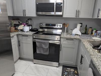 946 Delano Ct, Kissimmee, FL 34758 - kitchen with appliances with stainless steel finishes, light marble finish flooring, and light stone countertops