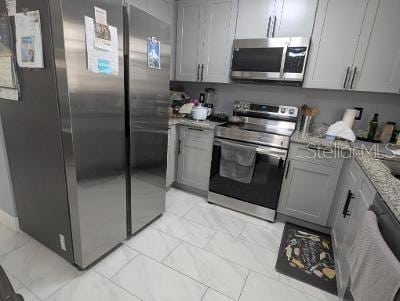 946 Delano Ct, Kissimmee, FL 34758 - kitchen featuring appliances with stainless steel finishes, light marble finish flooring, light stone counters, and gray cabinetry