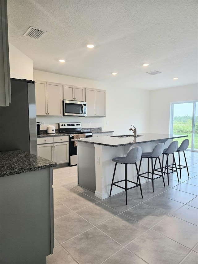 3886 Whitney Way, Haines City, FL 33844 - kitchen featuring stainless steel appliances, a sink, a kitchen breakfast bar, a textured ceiling, and light tile patterned flooring