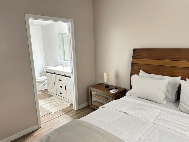 3301 Soho St Unit 104, Orlando, FL 32835 - bedroom featuring light wood-style floors, baseboards, ensuite bath, and a sink