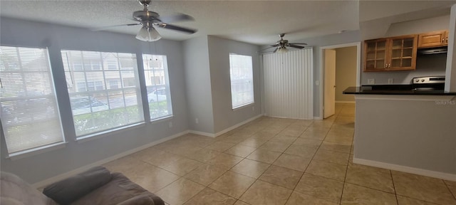 1023 S Hiawassee Rd Unit 4017, Orlando, FL 32835 - kitchen with stove, ceiling fan, dark countertops, glass insert cabinets, and light tile patterned floors
