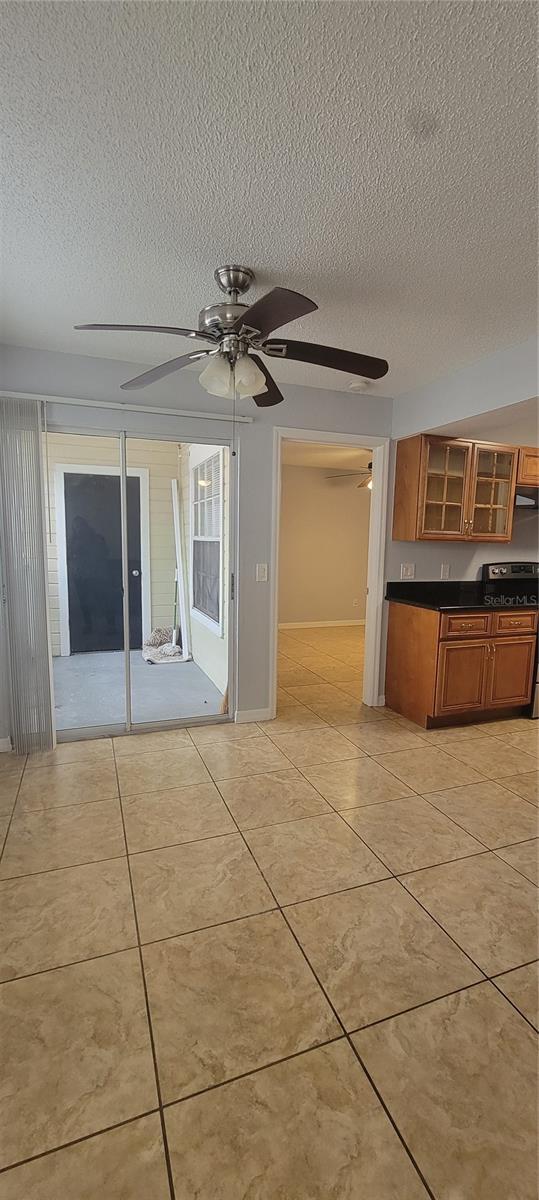 1023 S Hiawassee Rd Unit 4017, Orlando, FL 32835 - kitchen featuring a textured ceiling, brown cabinetry, dark countertops, a ceiling fan, and glass insert cabinets