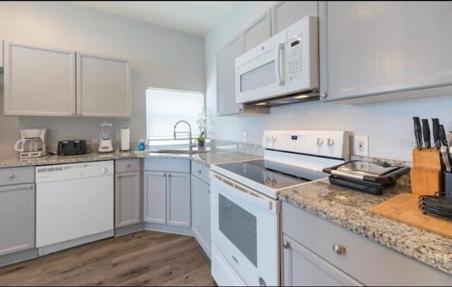 8121 Fan Palm Way, Kissimmee, FL 34747 - kitchen featuring white appliances, a sink, light wood-style floors, and light stone counters