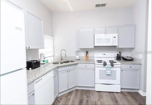 8121 Fan Palm Way, Kissimmee, FL 34747 - kitchen with white appliances, a sink, light wood-style floors, and light stone countertops