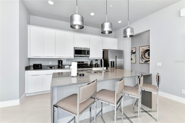 7770 Sandy Ridge Dr Unit 142, Kissimmee, FL 34747 - kitchen with stainless steel appliances, a breakfast bar, white cabinetry, a kitchen island with sink, and decorative light fixtures