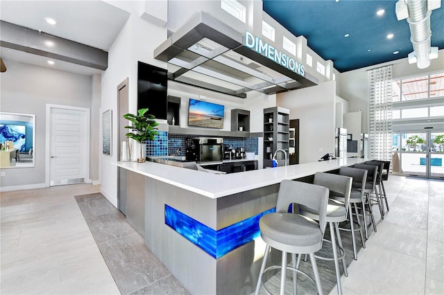 7770 Sandy Ridge Dr Unit 142, Kissimmee, FL 34747 - kitchen with a high ceiling, wall chimney range hood, recessed lighting, light tile patterned floors, and decorative backsplash