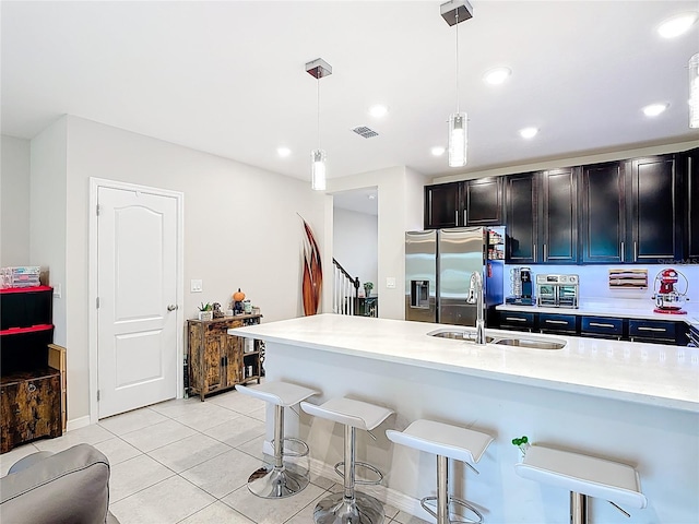 4850 Coral Castle Dr, Kissimmee, FL 34746 - kitchen featuring stainless steel fridge with ice dispenser, a kitchen bar, light countertops, decorative light fixtures, and light tile patterned floors