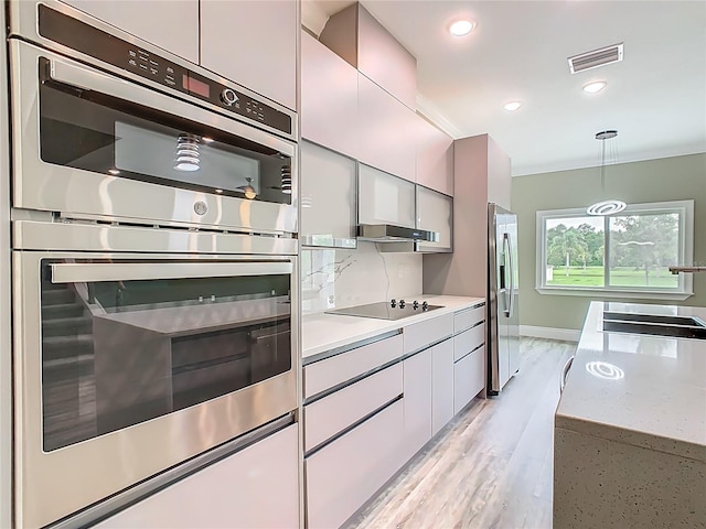 1870 Brentwood Ct, Davenport, FL 33837 - kitchen with stainless steel appliances, a sink, light wood-style flooring, light countertops, and hanging light fixtures