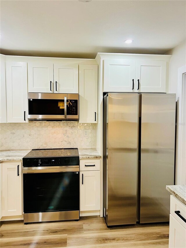 801 Leeward Way, Palm Harbor, FL 34685 - kitchen with stainless steel appliances, light wood finished floors, white cabinetry, and recessed lighting