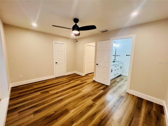 801 Leeward Way, Palm Harbor, FL 34685 - unfurnished bedroom with a sink, baseboards, wood finished floors, recessed lighting, and ensuite bathroom