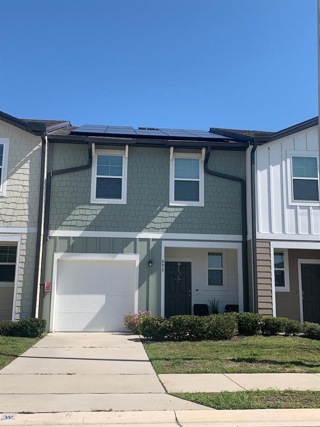 892 Grandin St, Davenport, FL 33837 - townhome / multi-family property with a garage, roof mounted solar panels, and board and batten siding