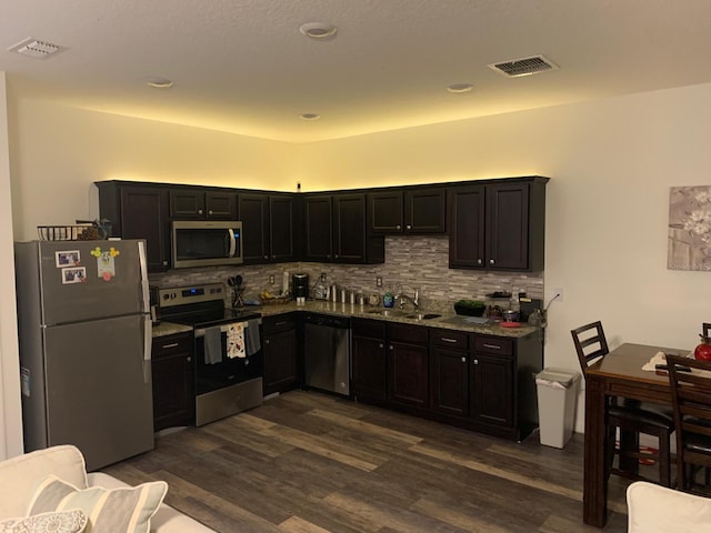 892 Grandin St, Davenport, FL 33837 - kitchen featuring stainless steel appliances, a sink, dark wood finished floors, decorative backsplash, and light stone counters