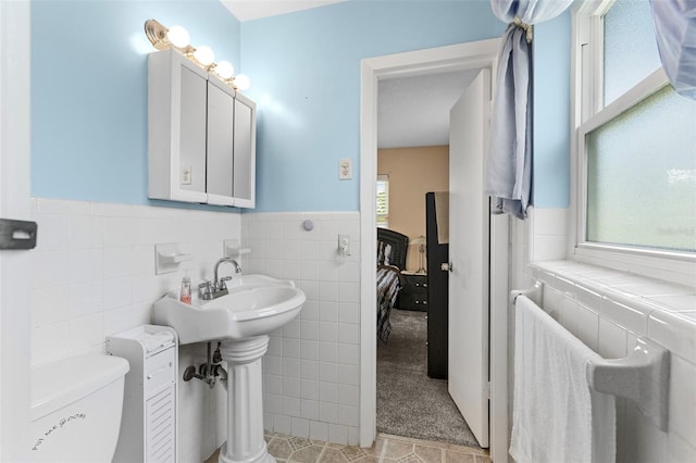 1566 Providence Blvd, Deltona, FL 32725 - bathroom with ensuite bath, tile walls, wainscoting, toilet, and tile patterned floors