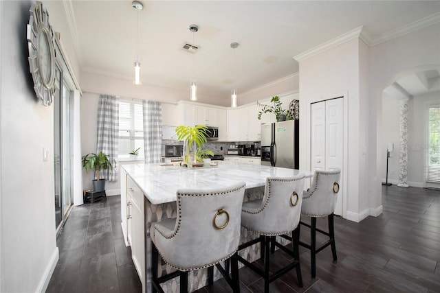 5231 Lemon Twist Ln, Windermere, FL 34786 - kitchen with appliances with stainless steel finishes, arched walkways, white cabinetry, light stone countertops, and a large island