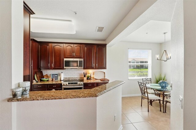 1225 Bella Cara Ct Unit 1, Davenport, FL 33896 - kitchen featuring appliances with stainless steel finishes, decorative backsplash, a peninsula, light tile patterned floors, and baseboards
