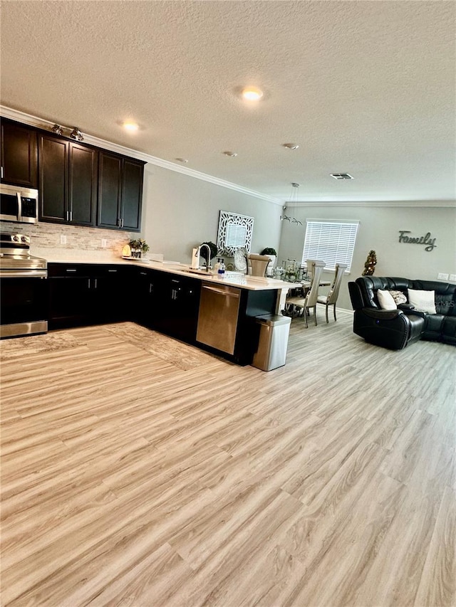 1016 Cascade Dr, Davenport, FL 33837 - kitchen with appliances with stainless steel finishes, ornamental molding, a peninsula, open floor plan, and a textured ceiling
