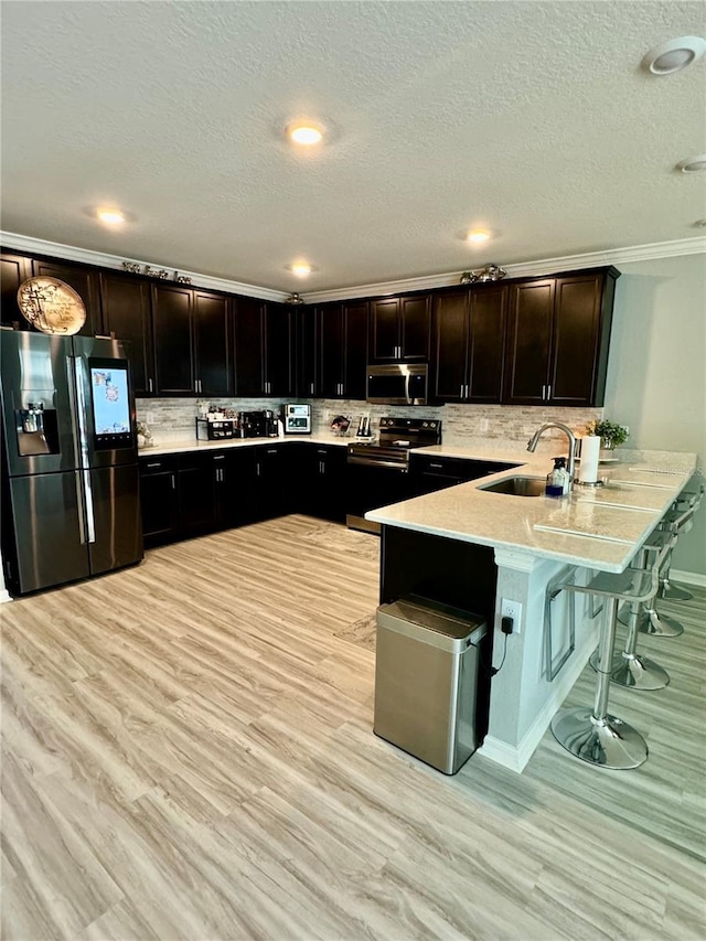 1016 Cascade Dr, Davenport, FL 33837 - kitchen featuring appliances with stainless steel finishes, a peninsula, light countertops, backsplash, and a breakfast bar area