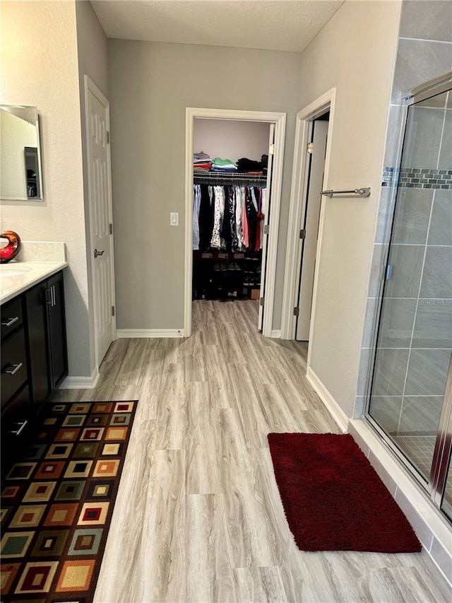 1016 Cascade Dr, Davenport, FL 33837 - full bathroom featuring vanity, a stall shower, a spacious closet, and wood finished floors