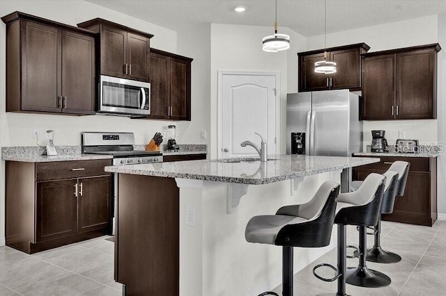 7622 Oakmoss Loop, Davenport, FL 33837 - kitchen featuring stainless steel appliances, a sink, a kitchen breakfast bar, light stone counters, and light tile patterned floors