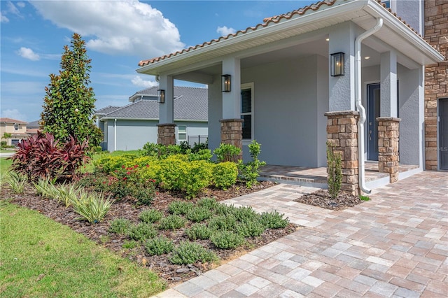 15600 Vetta Dr, Bella Collina, FL 34756 - property entrance with covered porch, stone siding, and stucco siding