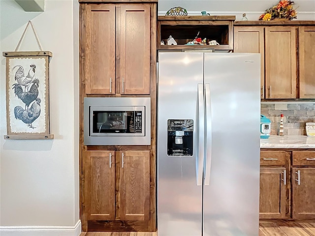 15311 Johns Lake Rd, Clermont, FL 34711 - kitchen featuring appliances with stainless steel finishes, light wood-style floors, decorative backsplash, and brown cabinets
