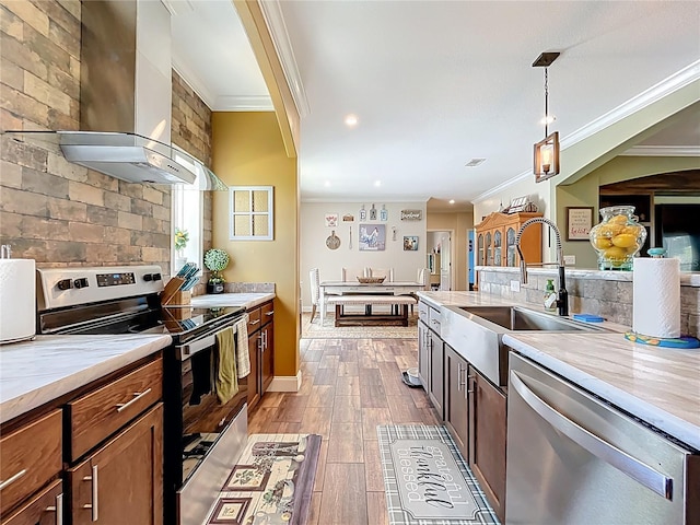 15311 Johns Lake Rd, Clermont, FL 34711 - kitchen with wall chimney range hood, stainless steel appliances, crown molding, a sink, and pendant lighting