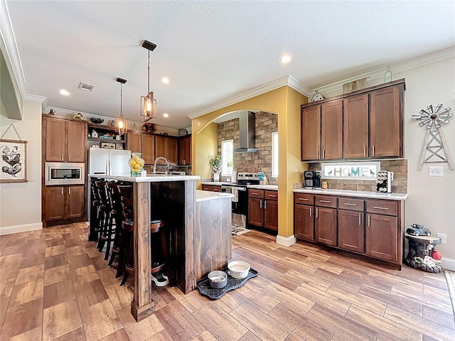 15311 Johns Lake Rd, Clermont, FL 34711 - kitchen with stainless steel appliances, wall chimney range hood, crown molding, light countertops, and light wood finished floors