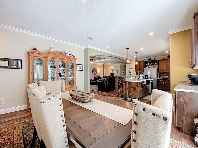 15311 Johns Lake Rd, Clermont, FL 34711 - dining area with ornamental molding, wood finished floors, ceiling fan, arched walkways, and baseboards