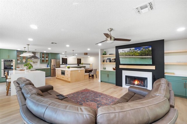 11951 Elbert St, Clermont, FL 34711 - living room featuring a textured ceiling, light wood-style flooring, recessed lighting, a fireplace, and ceiling fan
