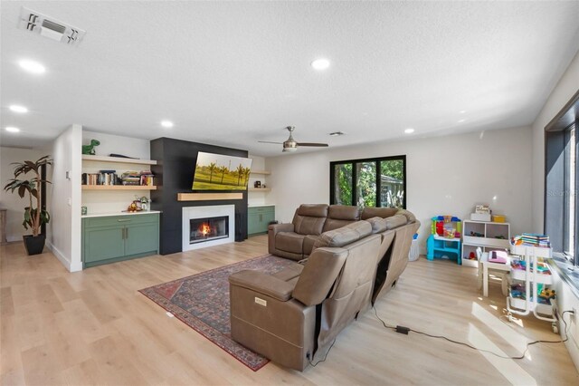 11951 Elbert St, Clermont, FL 34711 - living area with a glass covered fireplace, light wood-type flooring, recessed lighting, ceiling fan, and a textured ceiling