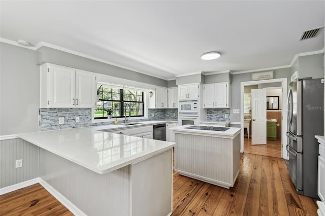 16 Pine Forest Dr, Haines City, FL 33844 - kitchen featuring black appliances, a peninsula, light countertops, dark wood-type flooring, and backsplash