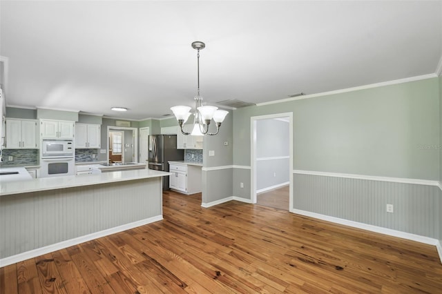 16 Pine Forest Dr, Haines City, FL 33844 - kitchen with white appliances, backsplash, a chandelier, light countertops, and ornamental molding