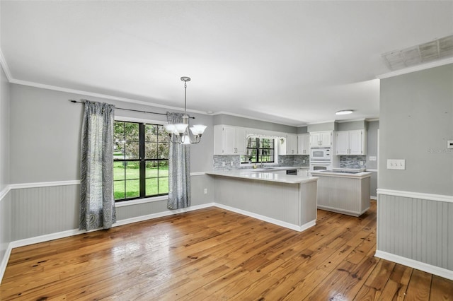 16 Pine Forest Dr, Haines City, FL 33844 - kitchen with a peninsula, white appliances, light wood-style flooring, light countertops, and backsplash
