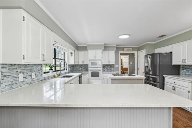 16 Pine Forest Dr, Haines City, FL 33844 - kitchen with white appliances, backsplash, a peninsula, light stone counters, and crown molding