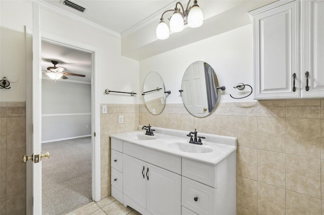16 Pine Forest Dr, Haines City, FL 33844 - full bathroom featuring tile walls, crown molding, double vanity, a ceiling fan, and wainscoting