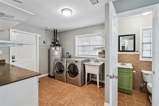 16 Pine Forest Dr, Haines City, FL 33844 - laundry room featuring water heater, washing machine and dryer, tile walls, and light tile patterned floors