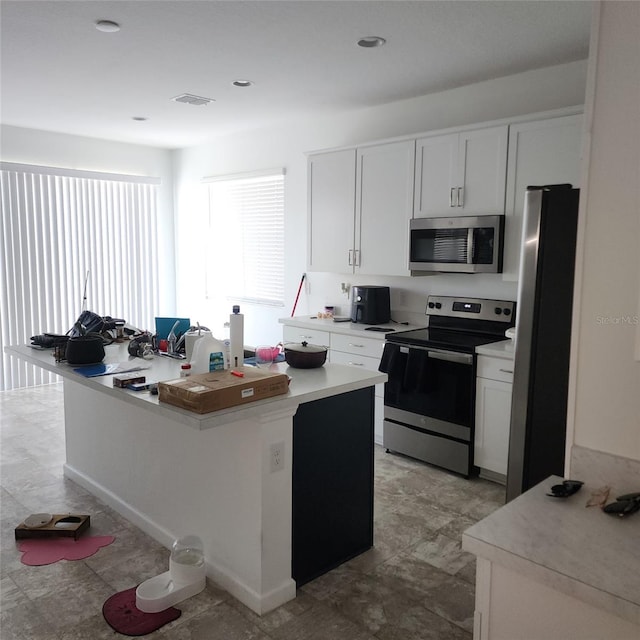 312 Lake Smart Cir, Winter Haven, FL 33881 - kitchen with stainless steel appliances, light countertops, a center island, and white cabinetry