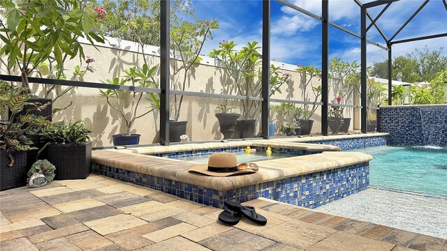148 Whirlaway Dr, Davenport, FL 33837 - view of swimming pool featuring glass enclosure, a pool with connected hot tub, and a patio area