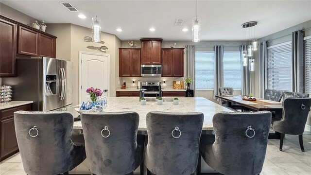 148 Whirlaway Dr, Davenport, FL 33837 - kitchen featuring appliances with stainless steel finishes, a center island with sink, light tile patterned flooring, hanging light fixtures, and recessed lighting