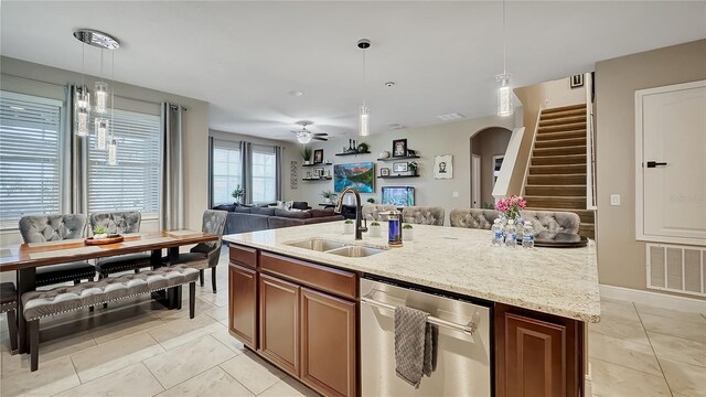 148 Whirlaway Dr, Davenport, FL 33837 - kitchen featuring stainless steel dishwasher, arched walkways, open floor plan, decorative light fixtures, and light stone countertops