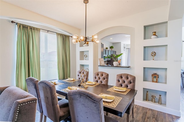 8491 Oasis Key Cv, Kissimmee, FL 34747 - dining room with a chandelier, wood finished floors, built in shelves, arched walkways, and baseboards
