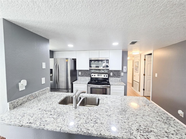 2735 N Poinciana Blvd Unit 95, Kissimmee, FL 34746 - kitchen with stainless steel appliances, a sink, white cabinets, light stone counters, and a peninsula