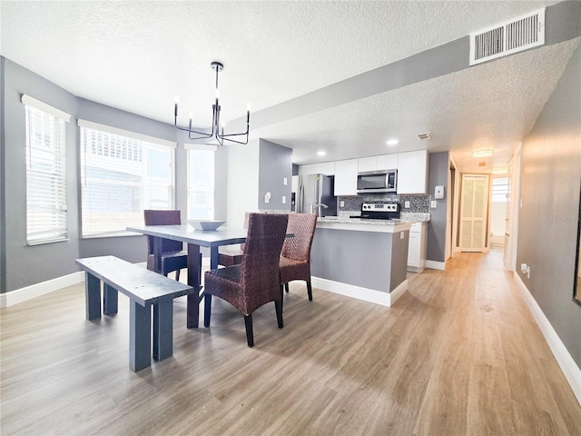 2735 N Poinciana Blvd Unit 95, Kissimmee, FL 34746 - dining space featuring a textured ceiling, a chandelier, light wood finished floors, and baseboards