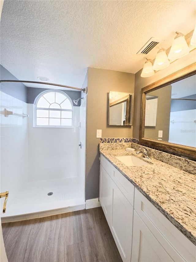 2735 N Poinciana Blvd Unit 95, Kissimmee, FL 34746 - full bathroom featuring wood finished floors, a shower, vanity, a textured ceiling, and baseboards