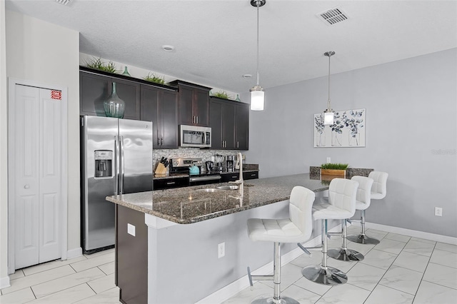 1578 Slice Way, Davenport, FL 33896 - kitchen featuring stainless steel appliances, a sink, a breakfast bar area, tasteful backsplash, and dark stone counters