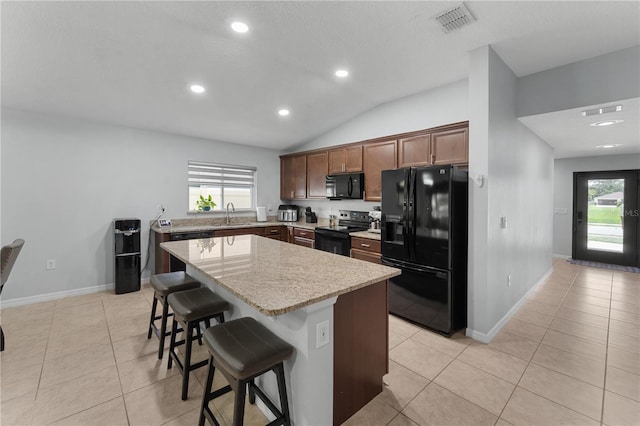 2461 Bulrush Dr, Saint Cloud, FL 34769 - kitchen featuring black appliances, a kitchen island, a kitchen breakfast bar, light tile patterned floors, and recessed lighting